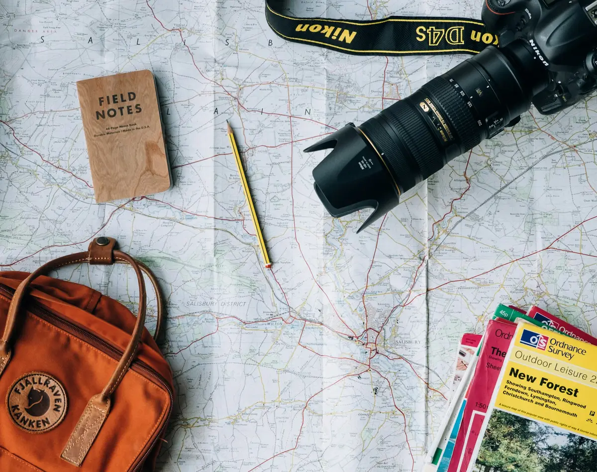 Mapa, câmera, caderno e mochila organizados para uma viagem